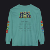A teal long-sleeve t-shirt with a humorous 'HOC Slots' gaming score printed on the back, featuring colorful dice graphics on the sleeves and a detailed text list of gaming achievements in the center.