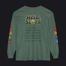 A sage green long-sleeve t-shirt with a humorous 'HOC SLOTS 10' graphic on the back, featuring gaming-themed text and colorful hexagonal icons down both sleeves.