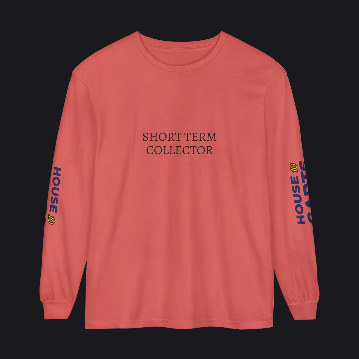 A coral pink long-sleeve t-shirt with 'SHORT TERM COLLECTOR' printed in black serif font on the chest. The left sleeve features 'HOUSE OF CARDS' printed vertically in blue and yellow, and the right sleeve has a small yellow graphic.
