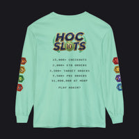 A mint green long-sleeve t-shirt shown from the back, featuring a humorous 'HOC Slots' casino-themed graphic with text detailing high player statistics and colorful hexagonal dice illustrations on the sleeves.