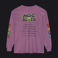 A purple long-sleeve t-shirt with a gaming-themed graphic on the back. The graphic features a 'HOC SLOTS 10' logo in a green and gold gradient, followed by dark gray text displaying various gaming statistics (checkouts, ETD orders, target orders, PKC orders, and a $1,000,000 at MSRP).