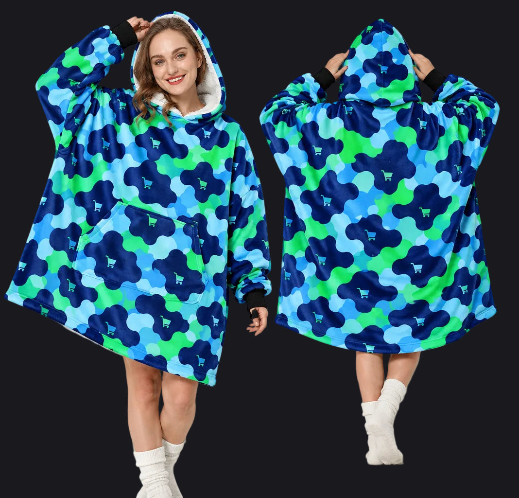 A woman models a hooded lounge blanket/pod in a studio setting, shown from the front and back, with inset close-ups of the hood and front pocket area. The product has a bold blue and green abstract pattern with a white sherpa-like hood lining and black cuffs.