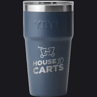 A dark slate blue YETI insulated tumbler with a stainless steel lid, featuring a custom graphic of a shopping cart with the text 'HOUSE 10 CARTS' printed in silver on the front.